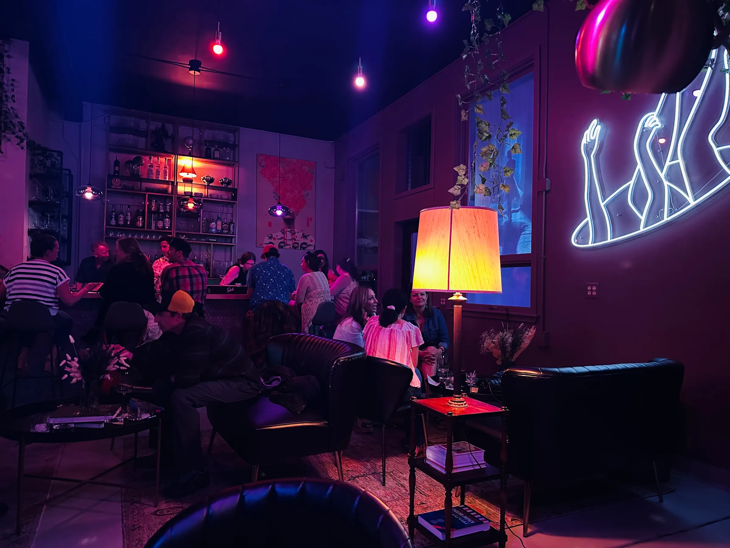 A low-lit cocktail lounge, people at the bar and in leather chairs